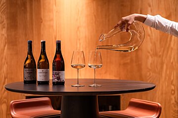 A person pouring wine from a decanter into a glass