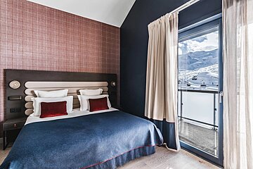 A hotel room with a bed and a view of the mountains