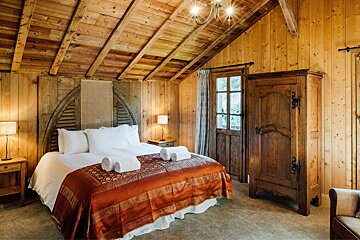 A bedroom with a wooden ceiling and a bed