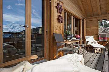 A balcony with chairs and a table with a view of the mountains