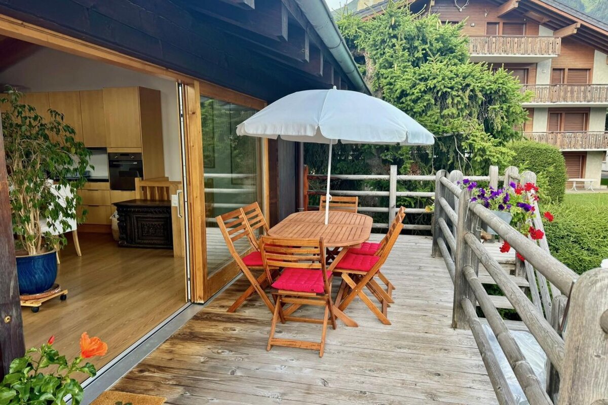 A wooden deck with a table and chairs under an umbrella