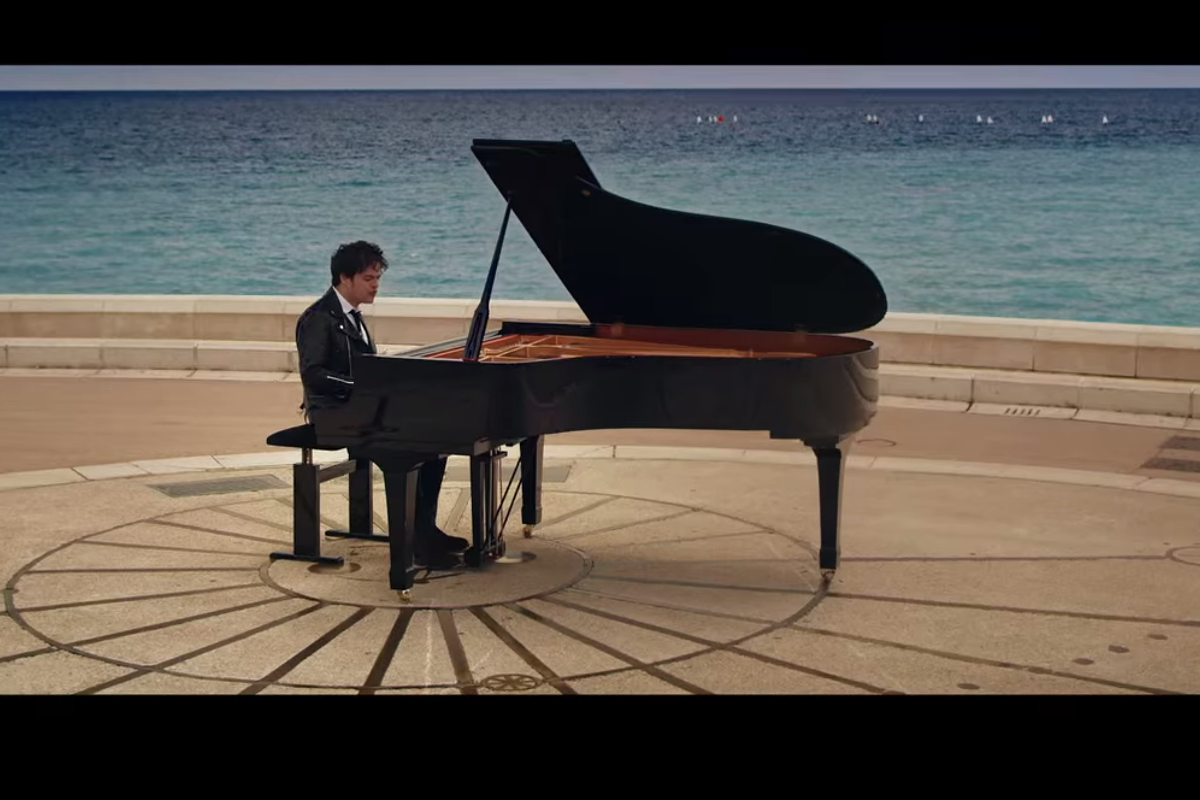 A man playing a piano in front of the ocean