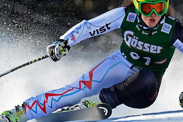 A woman is skiing down a snow covered slope