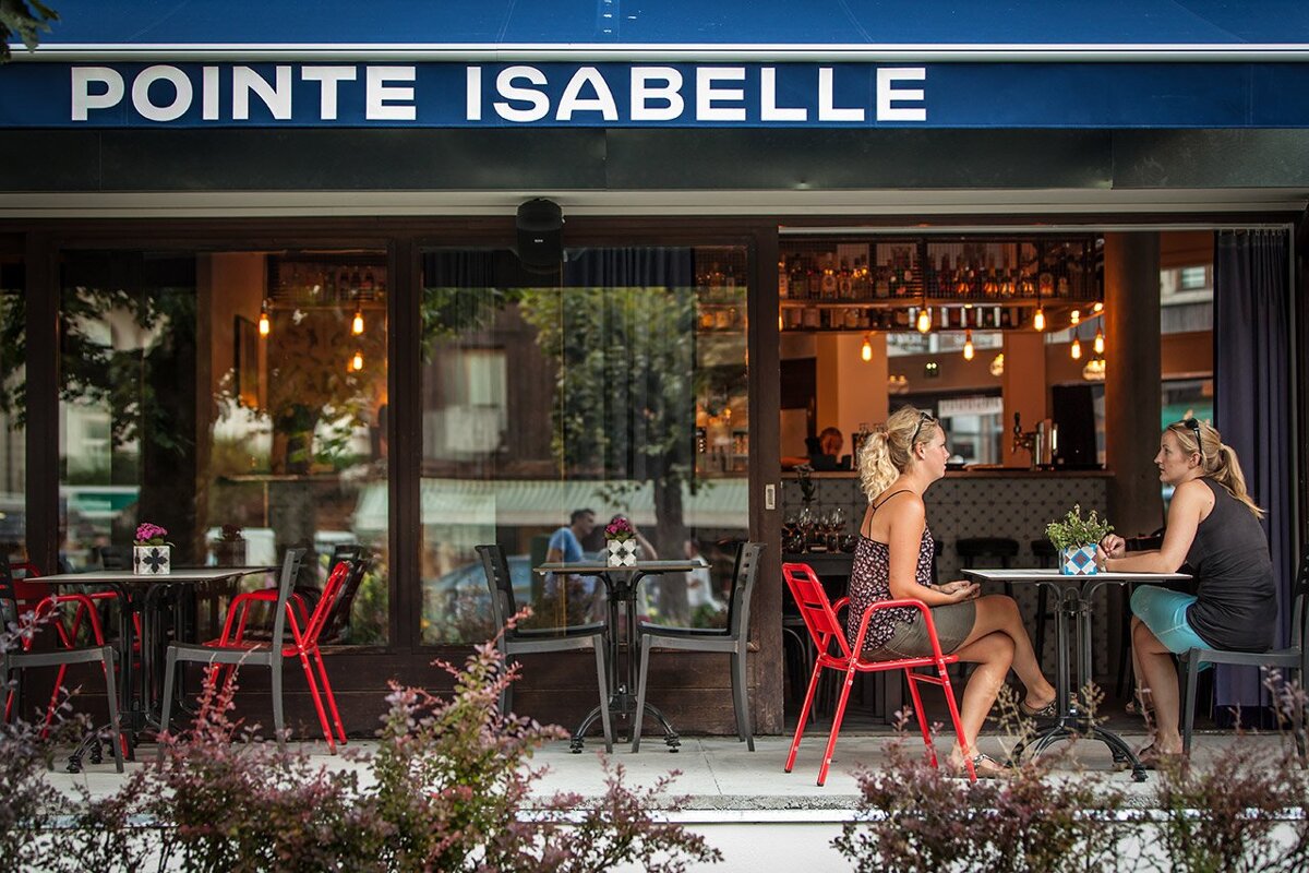 Two women sit at tables outside pointe isabelle