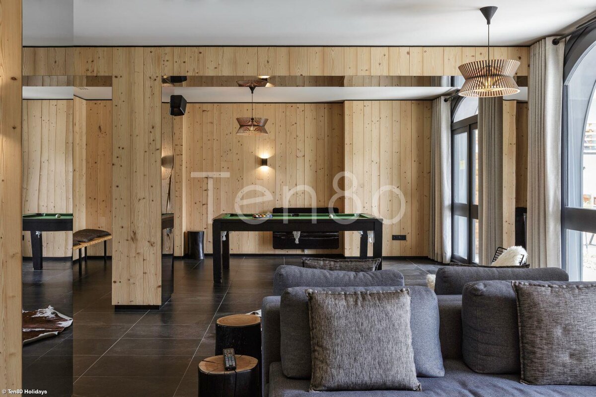 A living room with wood paneling and a pool table that says ten80