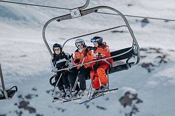 Skiers on a ski lift with the number 87 on the side