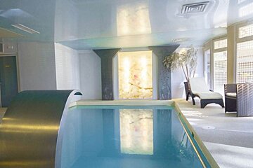 A large indoor swimming pool with a waterfall in the middle