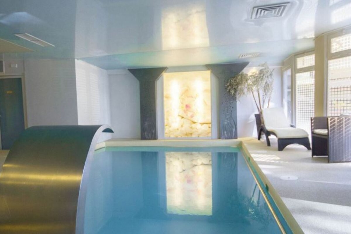 A large indoor swimming pool with a waterfall in the middle
