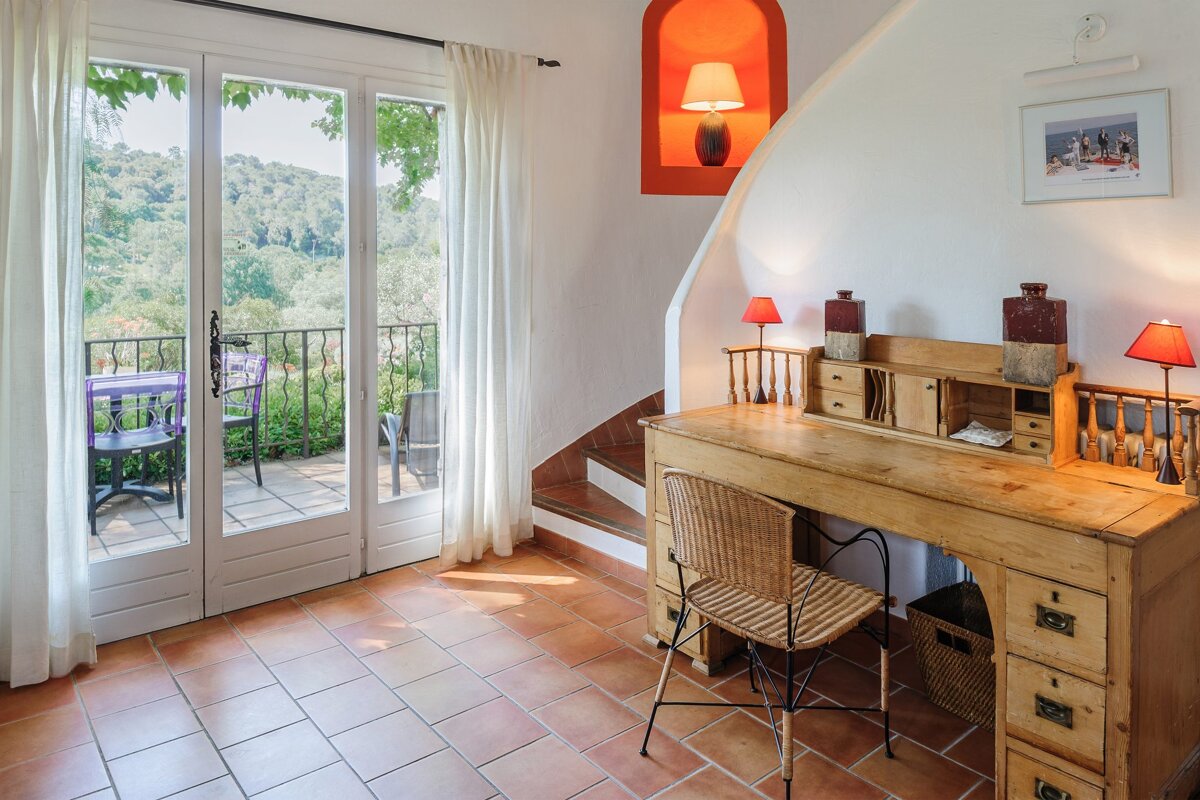 A wooden desk with a wicker chair in a room