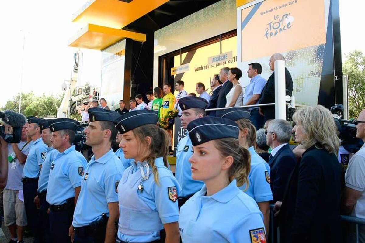 A group of police officers stand in front of a sign that says tour de france