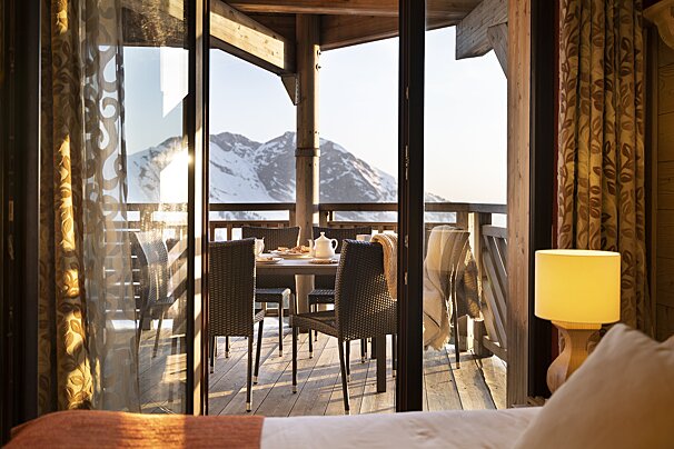 A balcony with a table and chairs and mountains in the background