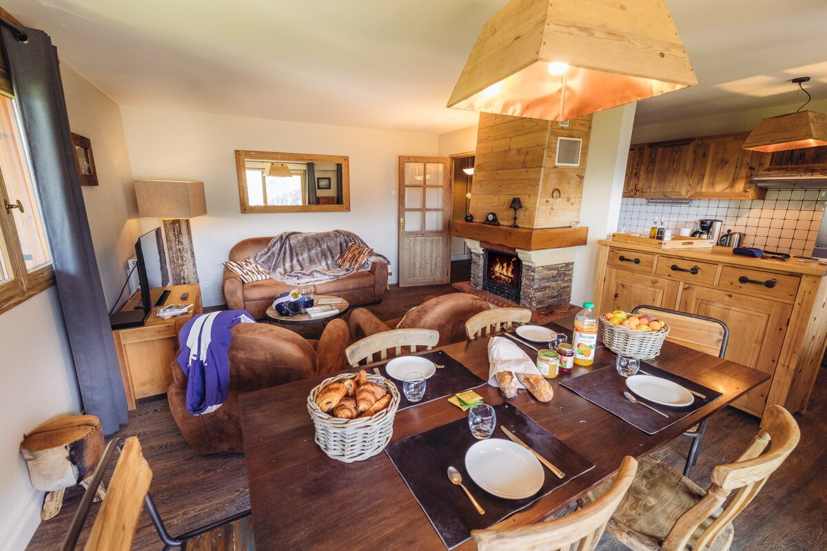 A dining table with a basket of bread and a bottle of orange juice on it