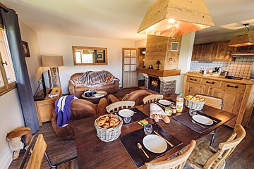A dining table with a basket of bread and a bottle of orange juice on it