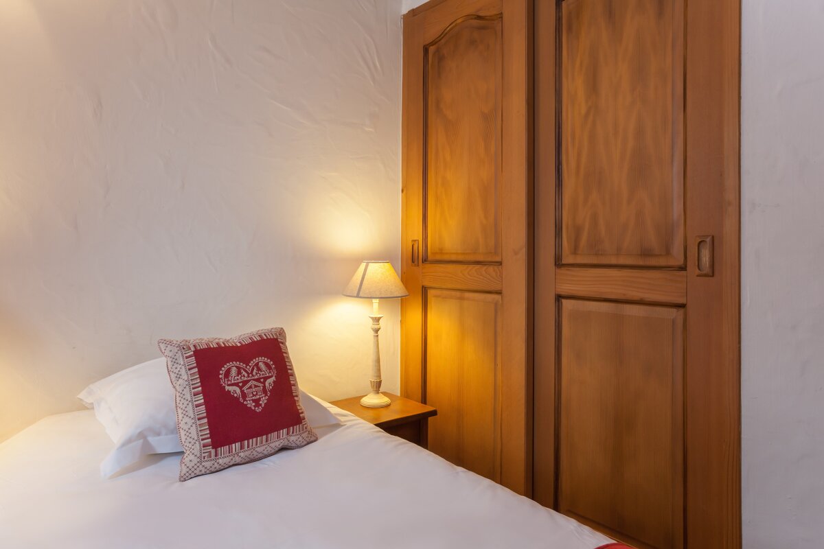 A pillow with a heart on it sits on a bed next to a lamp