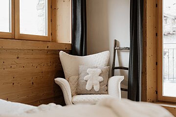 A white chair with a teddy bear pillow on it