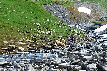 An image of a runner crossing a mountain river near chamonix mont blanc