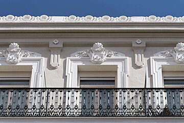 A white building with a balcony and a blue sky in the background