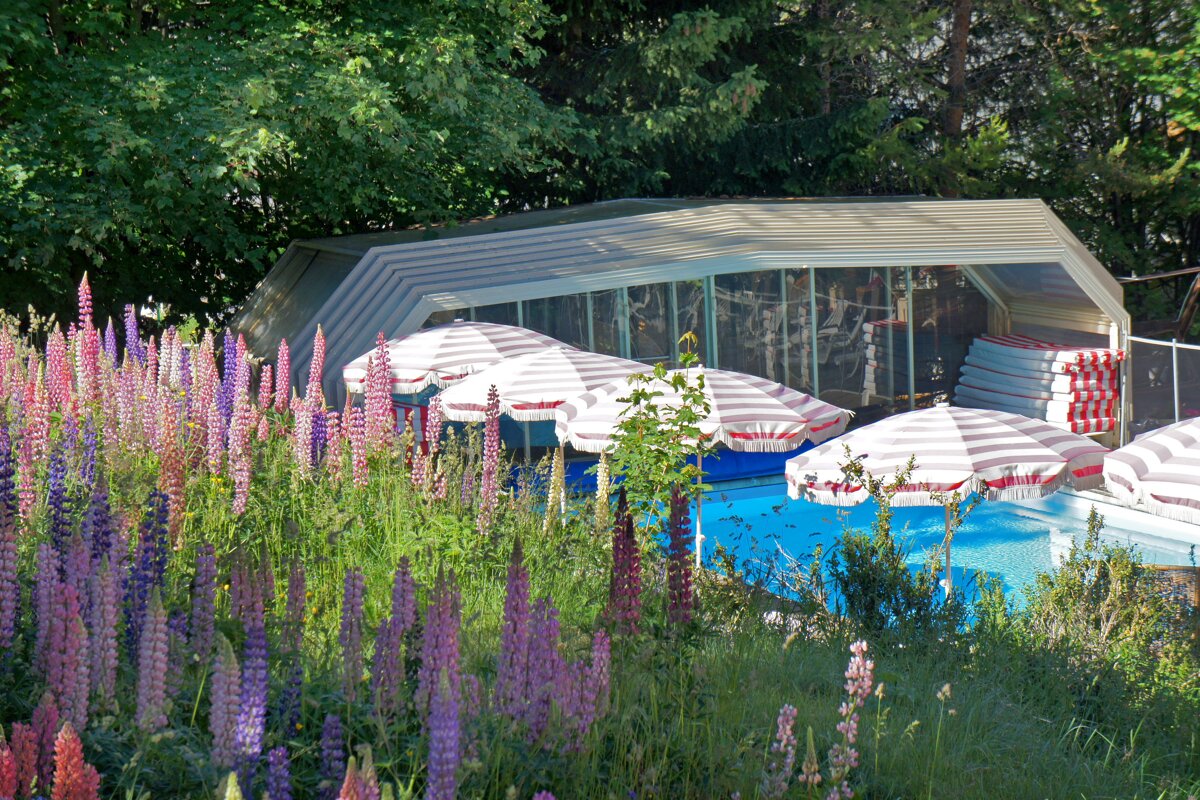 A swimming pool with striped umbrellas in front of it