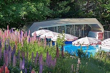 A swimming pool with striped umbrellas in front of it