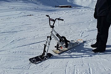 a man stood next to his snow scoot