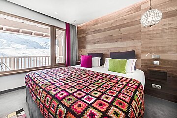 A bed with a colorful blanket and pillows in a hotel room