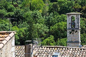 A tower with a bell on top of it surrounded by trees