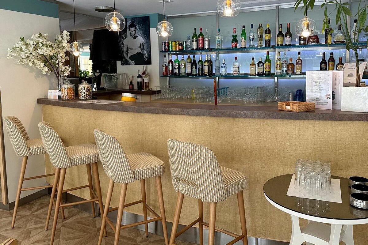 A row of bar stools are lined up in front of a bar