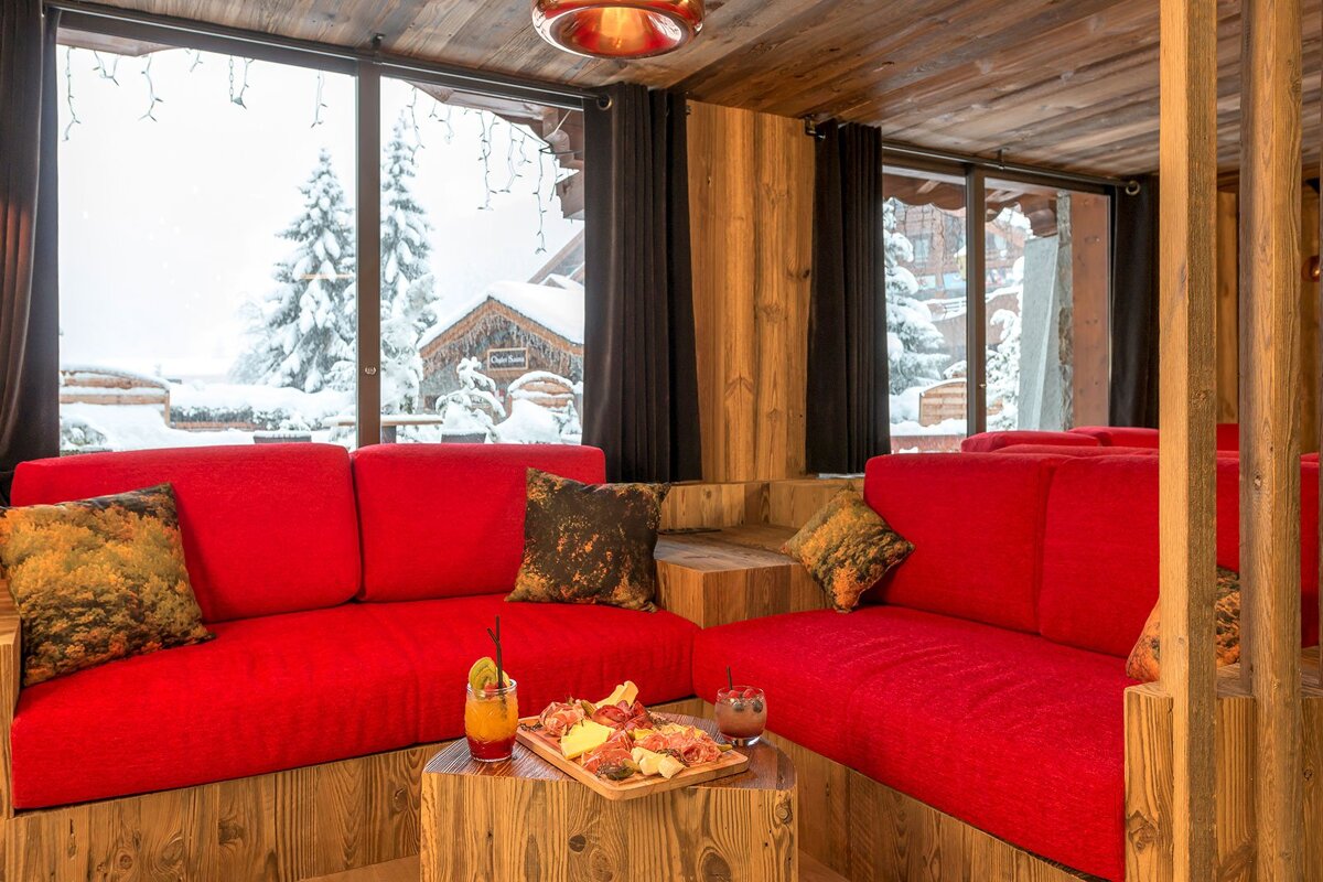 A living room with red couches and a table with a drink on it
