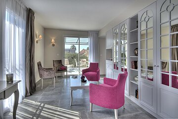 A living room with pink chairs and a white table