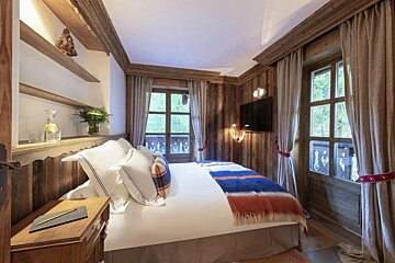 A bedroom with a bed and a television on the wall