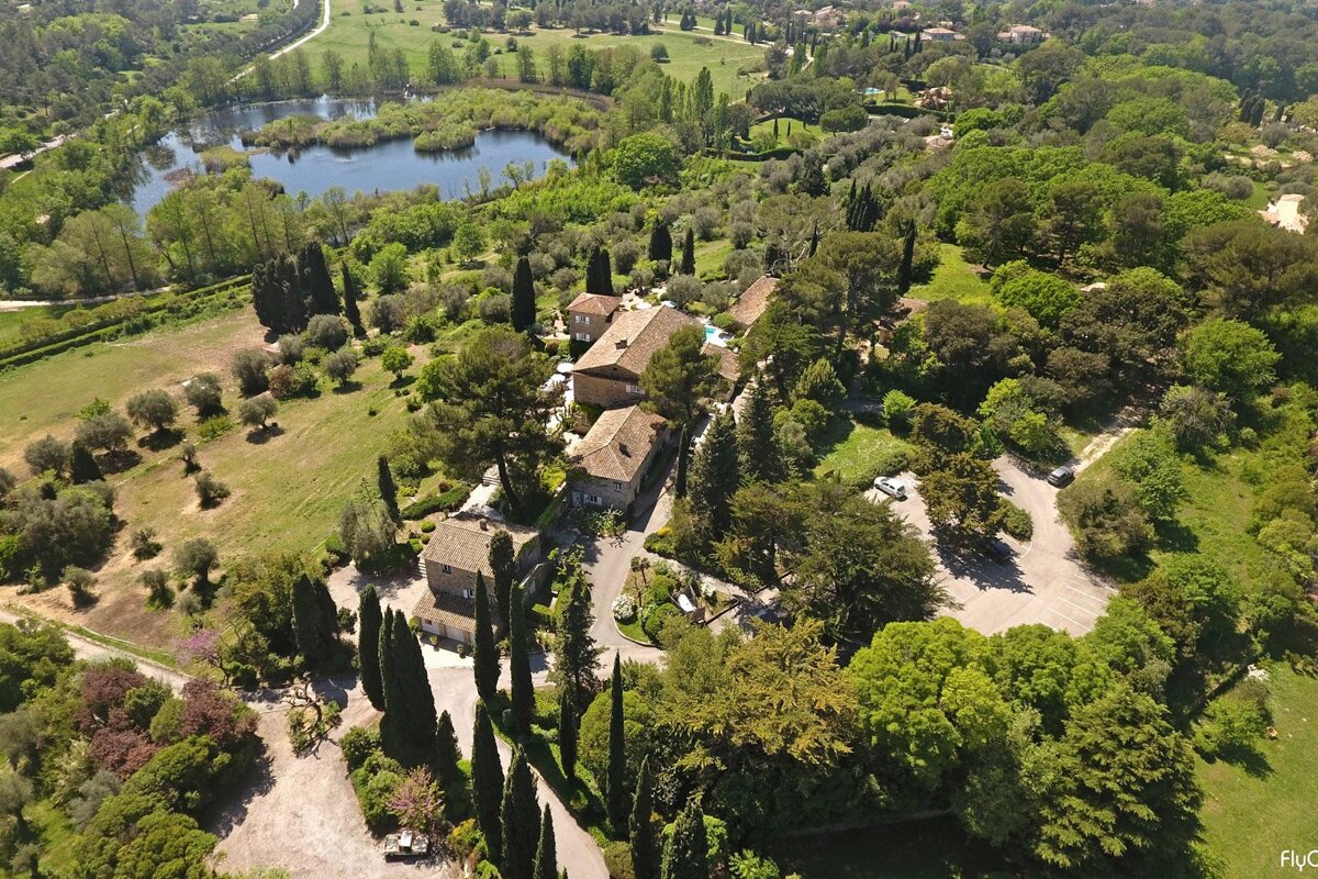 An aerial view of a house surrounded by trees and a lake