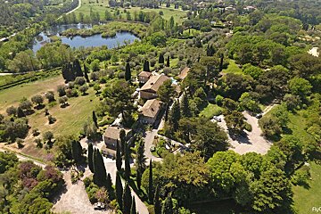 An aerial view of a house surrounded by trees and a lake