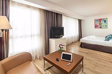 A hotel room with a bed and a table with a tablet on it