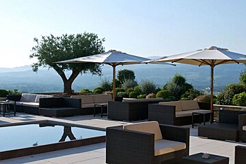 Terrace with sofa seating white umbrellas and feature pool