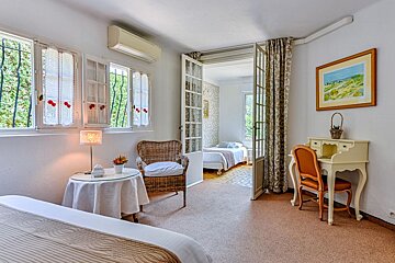 A bedroom with two beds and a desk with a picture on the wall