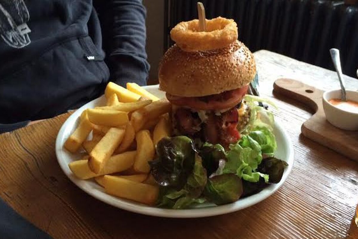 a huge burger with an onion ring on top