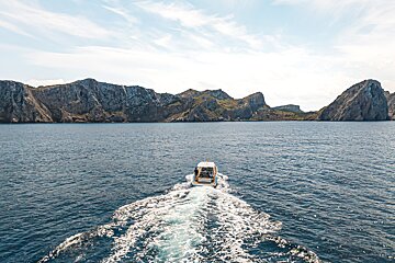 A boat in the ocean with mountains in the background