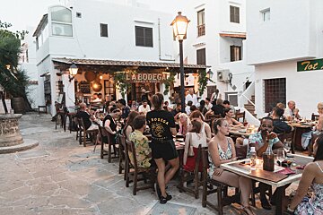 A group of people sitting at tables in front of a restaurant called la bodega