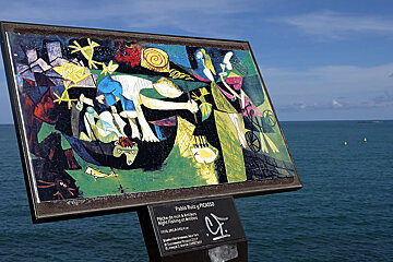 A painting by pablo picasso is displayed in front of the ocean