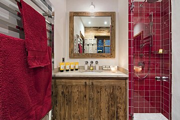 A bathroom with red tiles and wooden cabinets