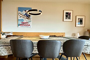 A dining room with a poster on the wall that says crans montana