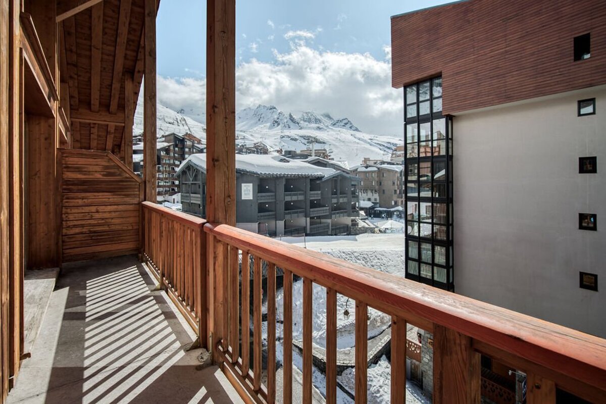 A balcony with a view of snowy mountains and buildings