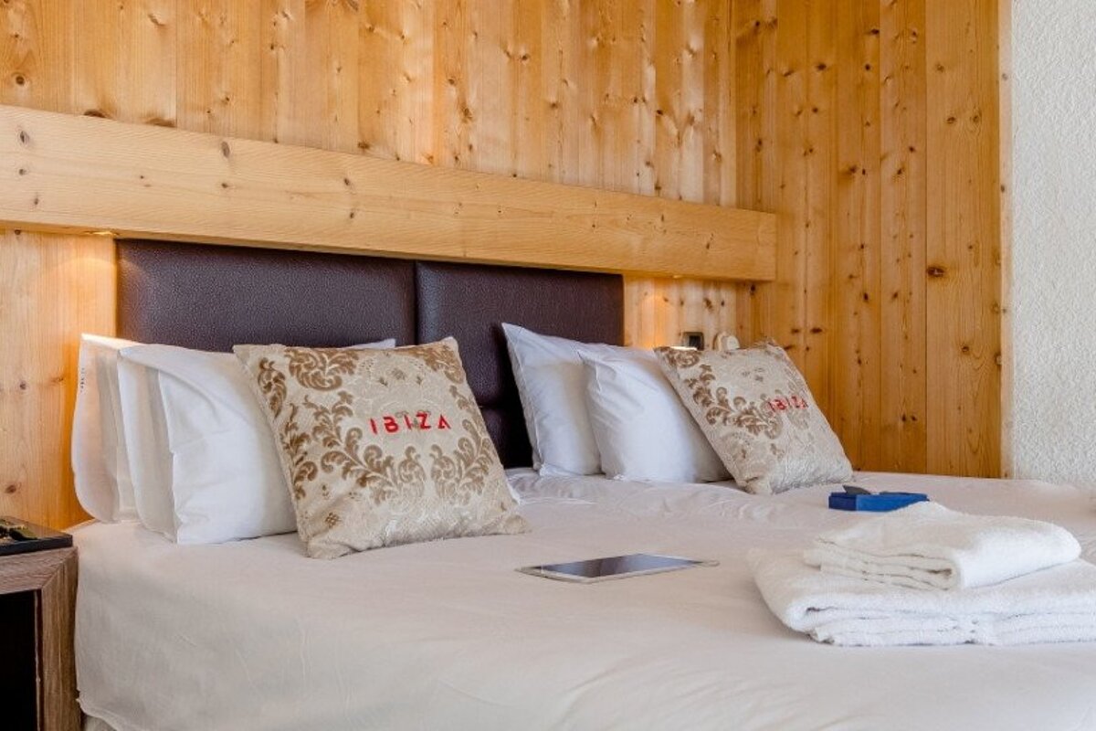 A bed with two pillows that say ibiza on them