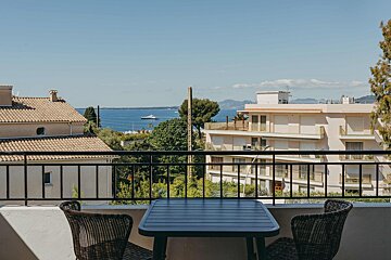 A table and chairs on a balcony overlooking the ocean