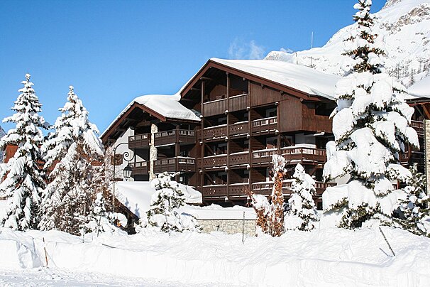 Snow covered trees in front of a building with balconies