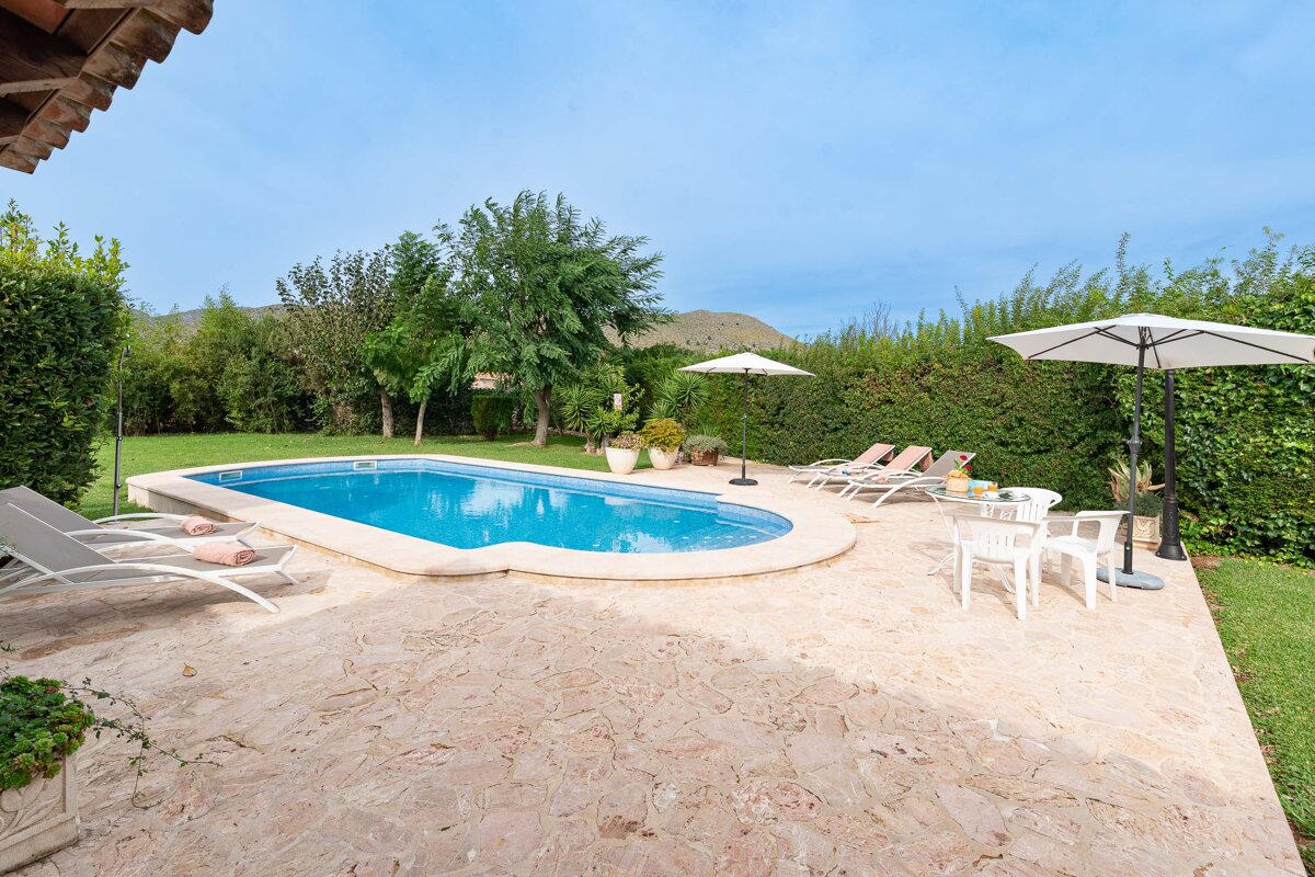 A large swimming pool is surrounded by chairs and umbrellas