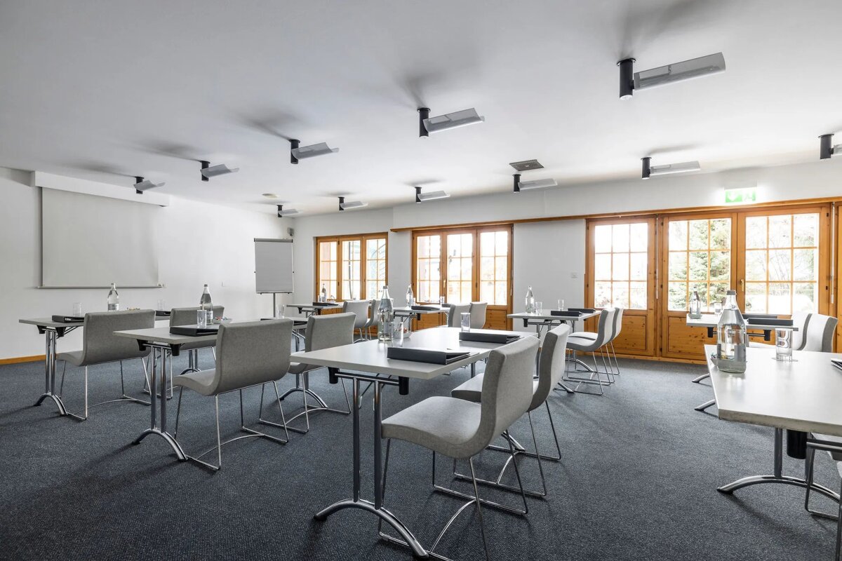 A conference room with tables and chairs and a projector screen