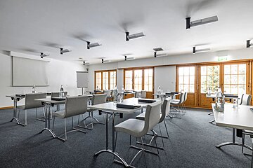 A conference room with tables and chairs and a projector screen