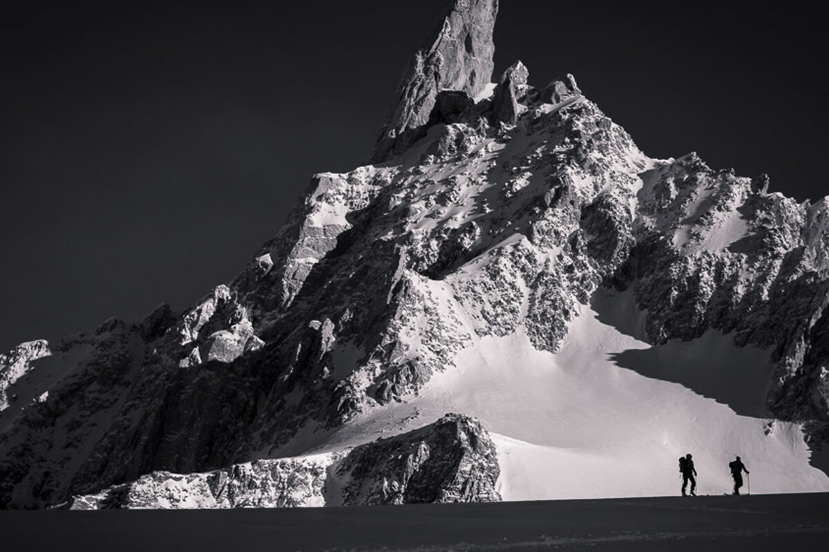 a black & white image of two silhouetted mountaineers