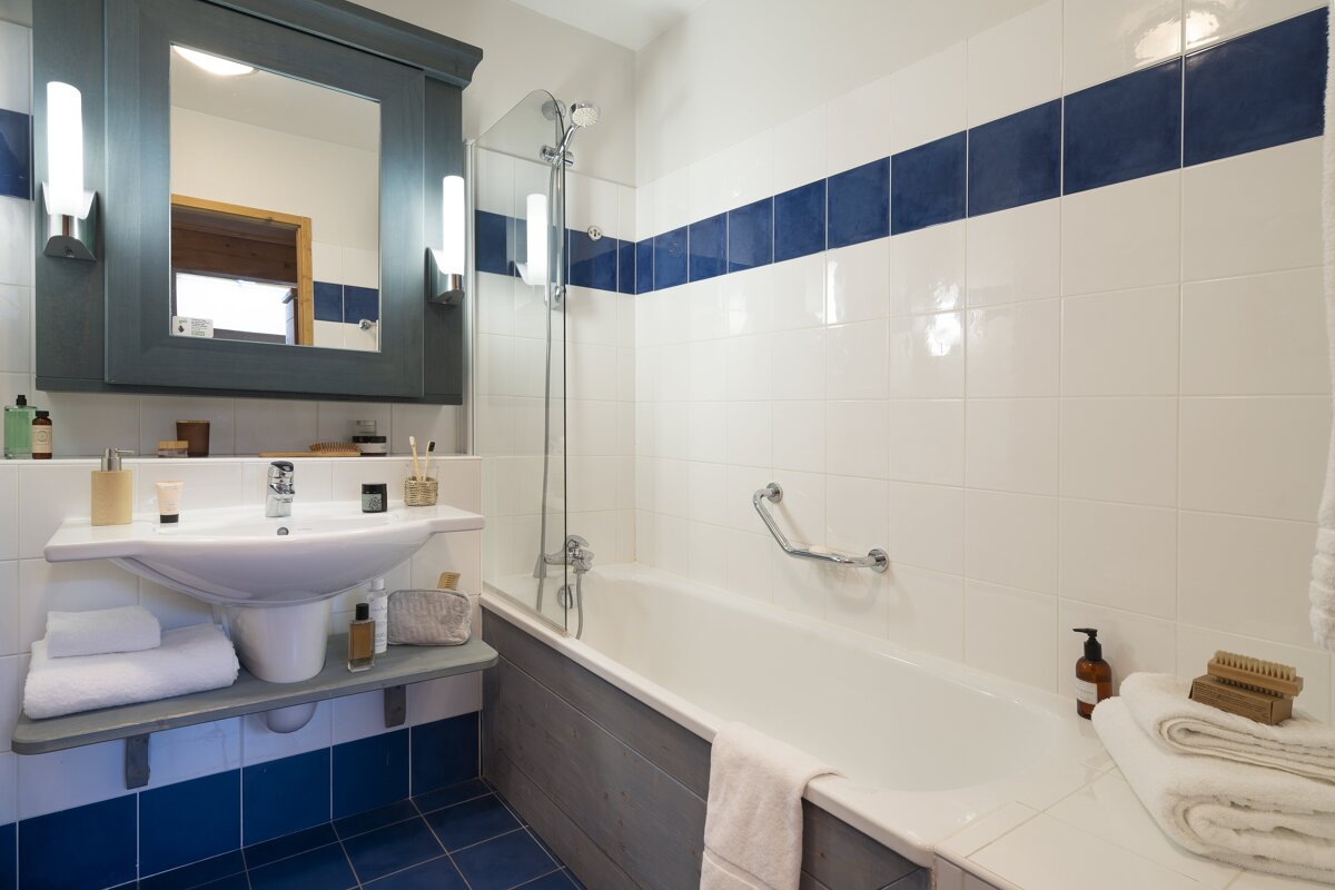 A bathroom with blue and white tiles and a sink and bathtub